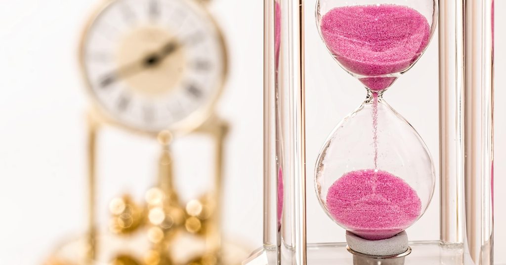 ピンクの砂が落ちる砂時計と、奥の置き時計