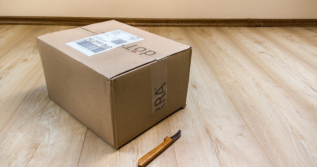 木の床に置いた、伝票の貼られた段ボール箱