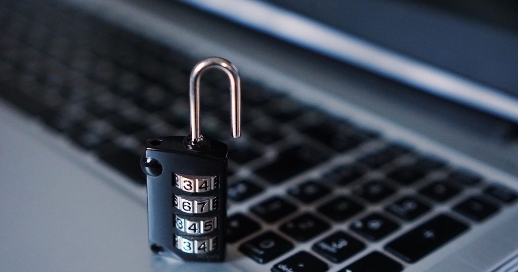 ノートパソコンのキーボードの上に置かれた、開いたダイヤル式の南京錠