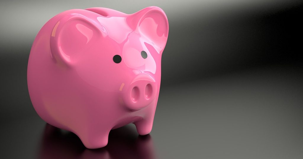 暗い背景に置かれた、ピンクの豚の貯金箱